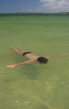 Kid floating in paradise lagoon  
