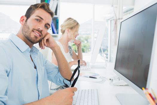 Side view of smiling casual young couple working on computer in a bright office