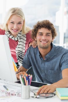 Portrait of a smiling casual business couple using computer in a bright office
