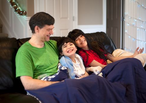 Father sitting on couch with daughter and disabled son. Son has cerebral palsy.