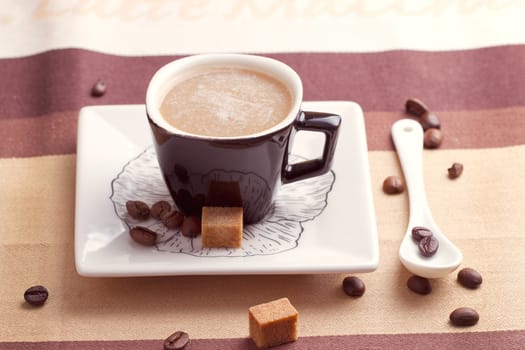 Cup of coffee with cube of brown sugar in a spoon close-up.