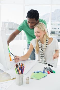 Smiling young casual couple using computer in a bright office