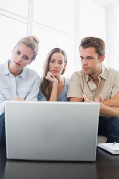 Three young people working on computer in a bright office