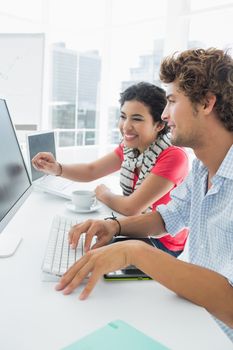 Side view of a casual couple using computer in a bright office