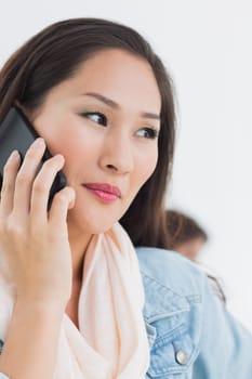 Closeup of a beautiful casual young woman using mobile phone in a bright office