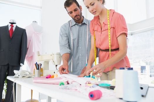 Male and female fashion designers at work in a bright studio