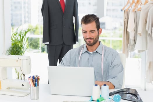 Young male fashion designer using laptop in the studio