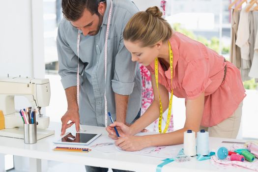 Male and female fashion designers using digital tablet in a bright studio