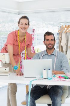 Male and female fashion designers with laptop at work in a bright studio