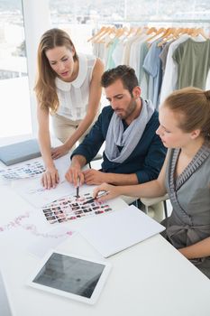 Three fashion designers discussing designs in a studio