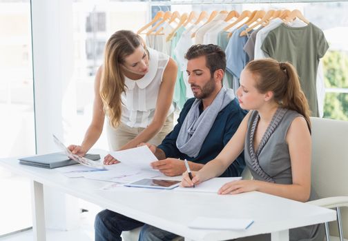 Three fashion designers discussing designs in a studio