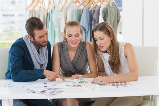 Three fashion designers discussing designs in a studio