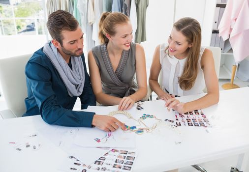 Three fashion designers discussing designs in a studio