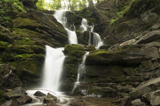 mountain waterfall runs over mossy stones