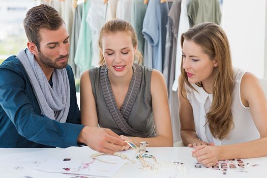 Three fashion designers discussing designs in a studio