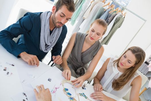 Three fashion designers discussing designs in a studio