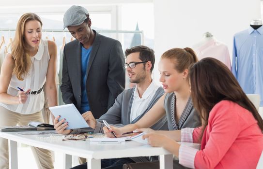 Group of fashion designers discussing designs in a studio