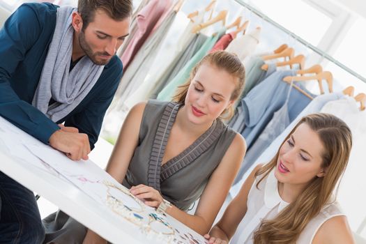 Three fashion designers discussing designs in a studio