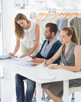 Three fashion designers discussing designs in a studio