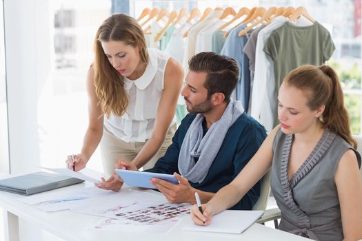 Three fashion designers discussing designs in a studio