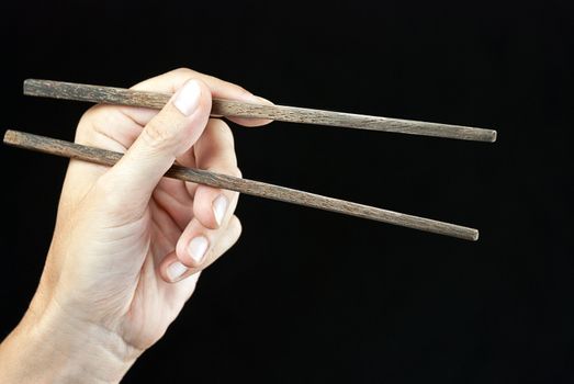 Close-up of a hand holding open chopsticks.