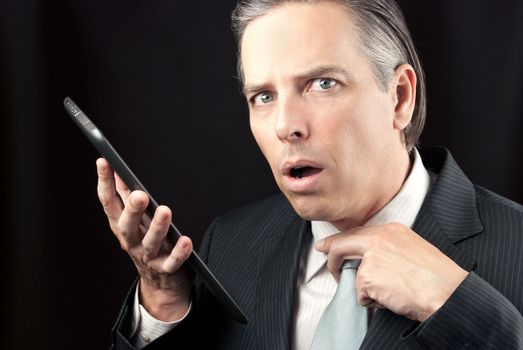 Close-up of a businessman using his tablet and looking to camera with concern