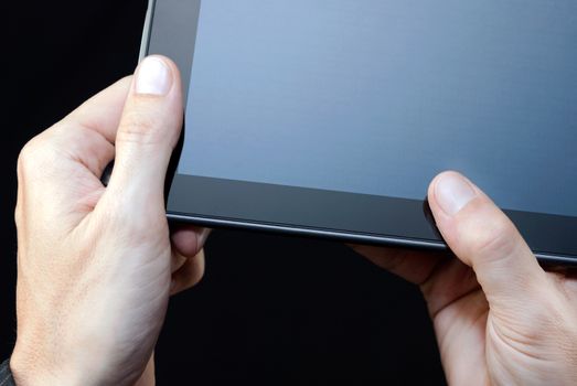 Close-up of a hand holding an unlit tablet, upper right.