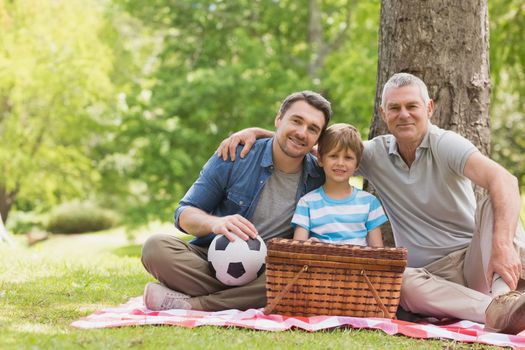 Portrait of grandfather father and son with picnic basket at the park