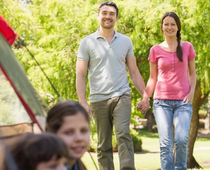 Blurred kids in tent with portrait of couple in background at park