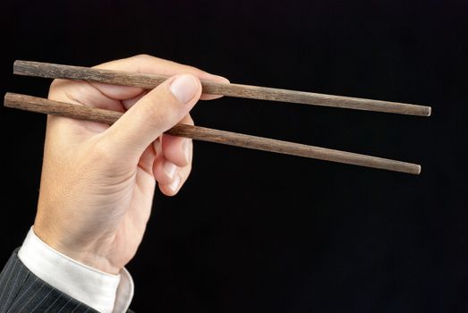Close-up of a businessman's hand holding chopsticks.