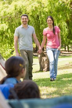 Blurred kids in tent with portrait of couple in background at park