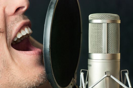 Super close-up of a man singing into a condenser microphone