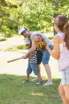 Family of three playing baseball in the park