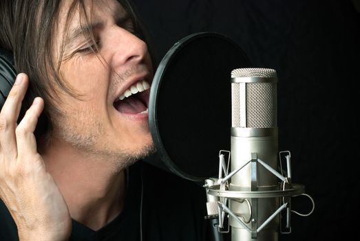 Close-up of a man singing into a condenser microphone.