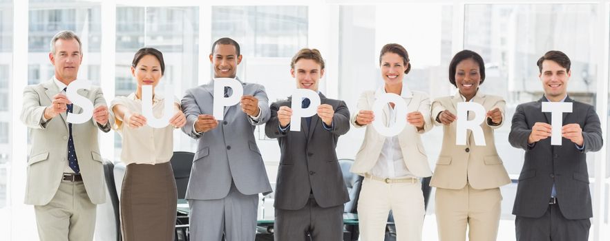 Diverse business team holding up letters spelling support in the office