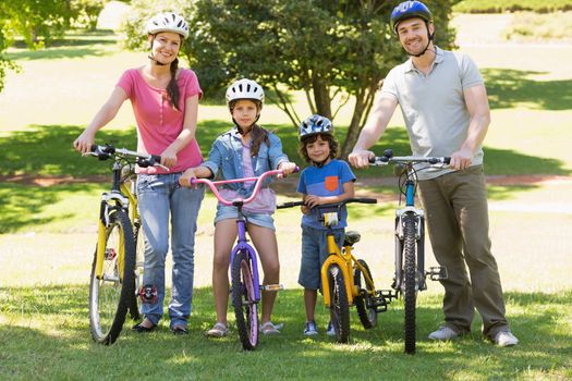 Full length portrait a family of four with bicycles in the park