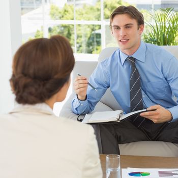 Young businessman scheduling with colleague sitting on couch in the office