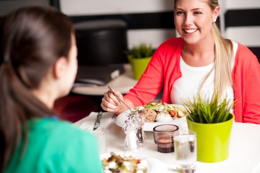 Cheerful young girls having dinner at a restaurant