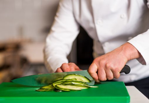 Chef chopping leek over green carving board