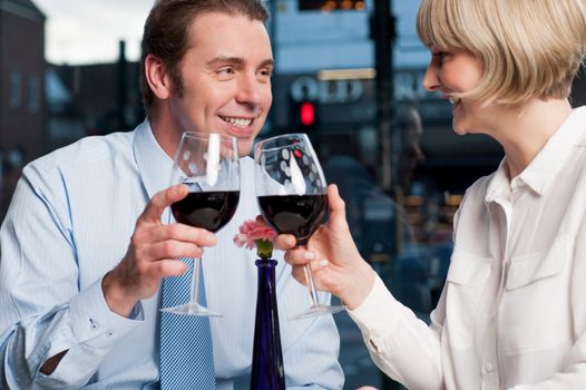 Attractive couple raises a glass of red wine in cafe