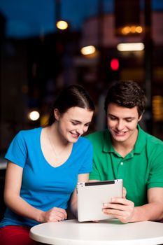 Happy young couple with a tablet computer in restaurant
