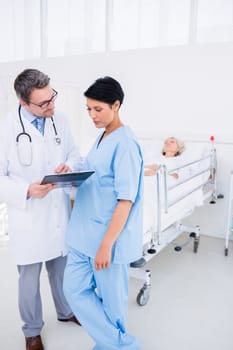 Doctors discussing reports with patient in background at the hospital