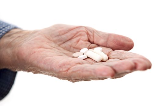 Closeup of senior hand holding medications over white