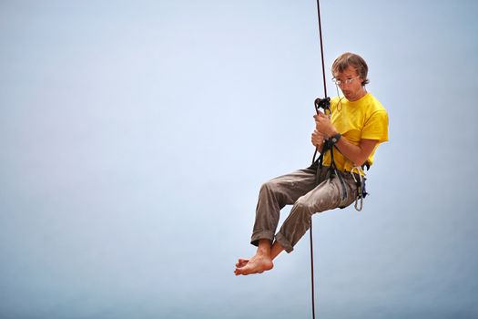 Rock climber belaying and being pulled up by another climber