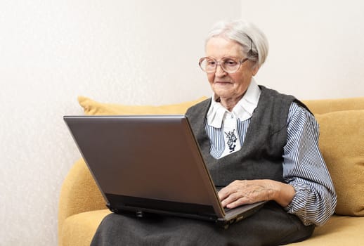 Senior woman using laptop computer while sitting on sofa