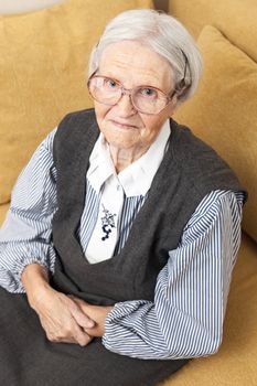 Portrait of a senior woman looking at the camera while sitting on sofa
