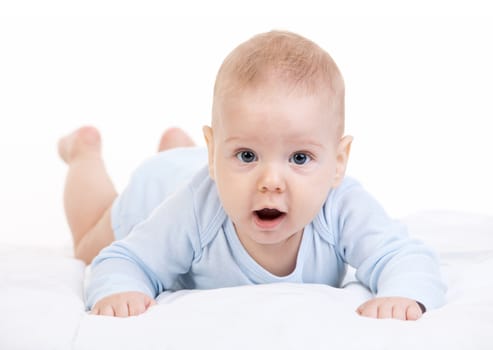 Little boy lying on stomach and looking at camera over white background