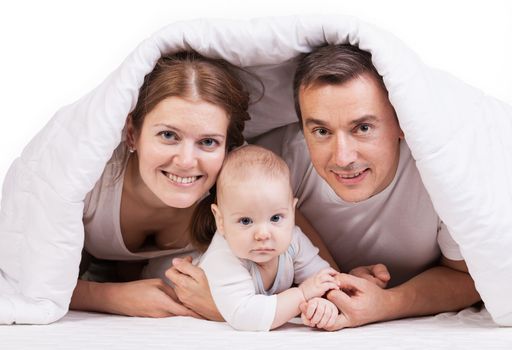 Young family with baby boy under blanket on bed over white