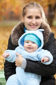 Young smiling woman with baby in autumn park