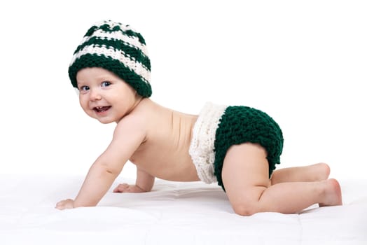 Happy baby boy in knitted hat crawling over white background